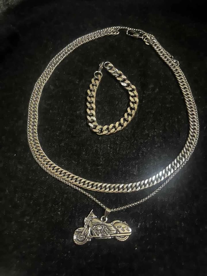 Conjunto de joyería incluye cadena con dije de motocicleta, cadena estilo cubano de 10 mm de ancho por 60 cms. de largo de acero inoxidable y esclava estilo cubana de 10 mm de ancho por 21 cms. de largo de acero inoxidable