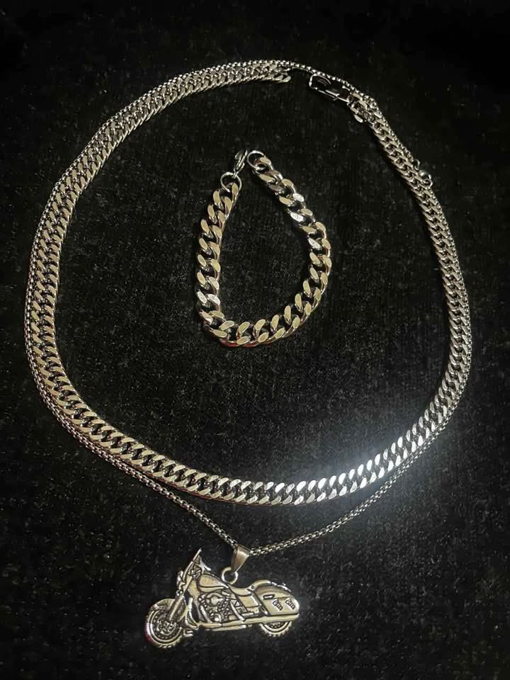Conjunto de joyería incluye cadena con dije de motocicleta, cadena estilo cubano de 10 mm de ancho por 60 cms. de largo de acero inoxidable y esclava estilo cubana de 10 mm de ancho por 21 cms. de largo de acero inoxidable