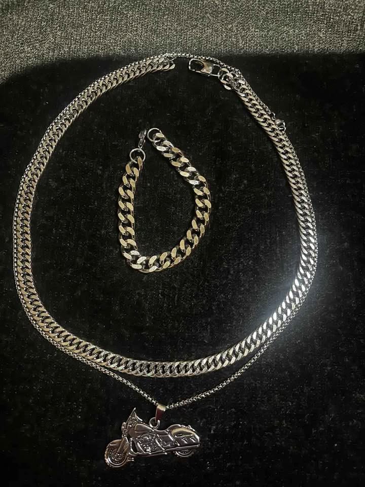 Conjunto de joyería incluye cadena con dije de motocicleta, cadena estilo cubano de 10 mm de ancho por 60 cms. de largo de acero inoxidable y esclava estilo cubana de 10 mm de ancho por 21 cms. de largo de acero inoxidable