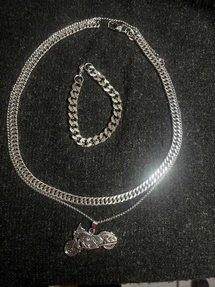 Conjunto de joyería incluye cadena con dije de motocicleta, cadena estilo cubano de 10 mm de ancho por 60 cms. de largo de acero inoxidable y esclava estilo cubana de 10 mm de ancho por 21 cms. de largo de acero inoxidable
