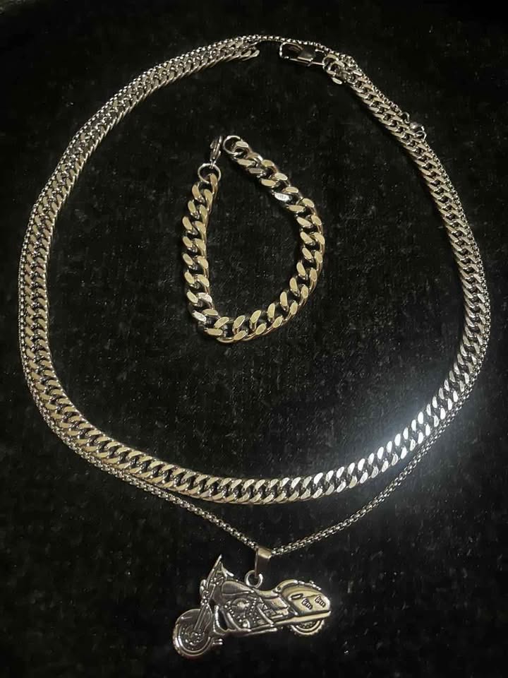 Conjunto de joyería incluye cadena con dije de motocicleta, cadena estilo cubano de 10 mm de ancho por 60 cms. de largo de acero inoxidable y esclava estilo cubana de 10 mm de ancho por 21 cms. de largo de acero inoxidable