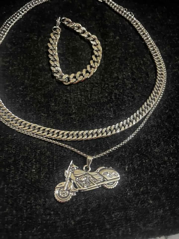 Conjunto de joyería incluye cadena con dije de motocicleta, cadena estilo cubano de 10 mm de ancho por 60 cms. de largo de acero inoxidable y esclava estilo cubana de 10 mm de ancho por 21 cms. de largo de acero inoxidable