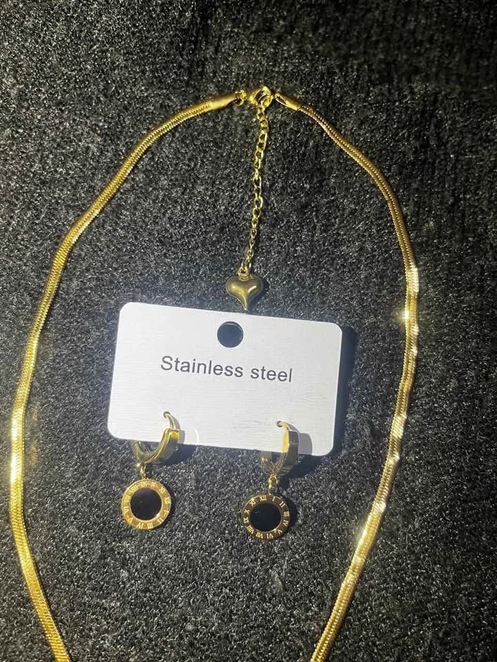 Conjunto de joyería incluye reloj, cadena con dije y par de aretes con detalle en color negro, acero inoxidable
