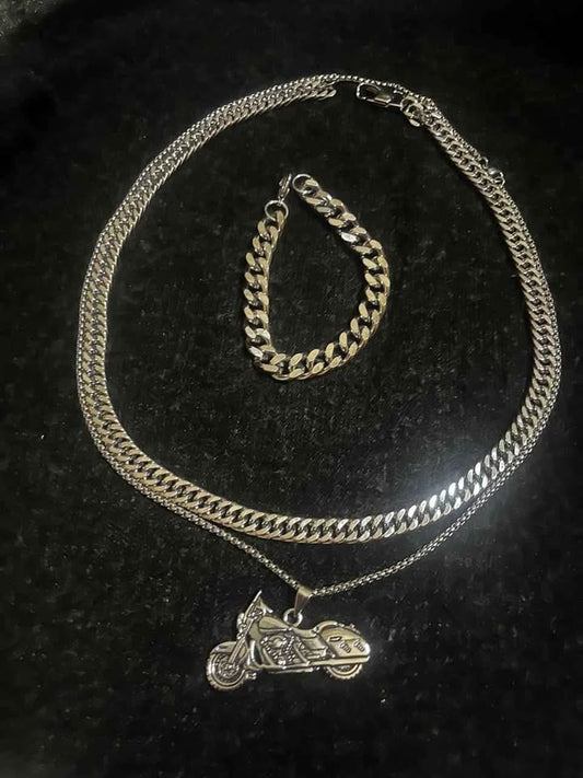 Conjunto de joyería incluye cadena con dije de motocicleta, cadena estilo cubano de 10 mm de ancho por 60 cms. de largo de acero inoxidable y esclava estilo cubana de 10 mm de ancho por 21 cms. de largo de acero inoxidable